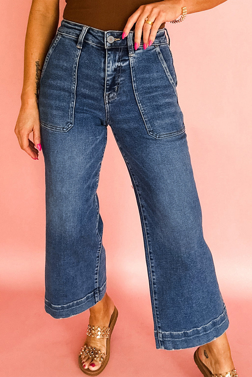 Person wearing blue wide-leg jeans on a pink background