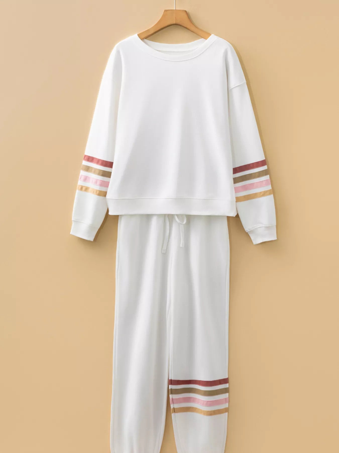 White sweatshirt and pants set with colorful stripes on a beige background
