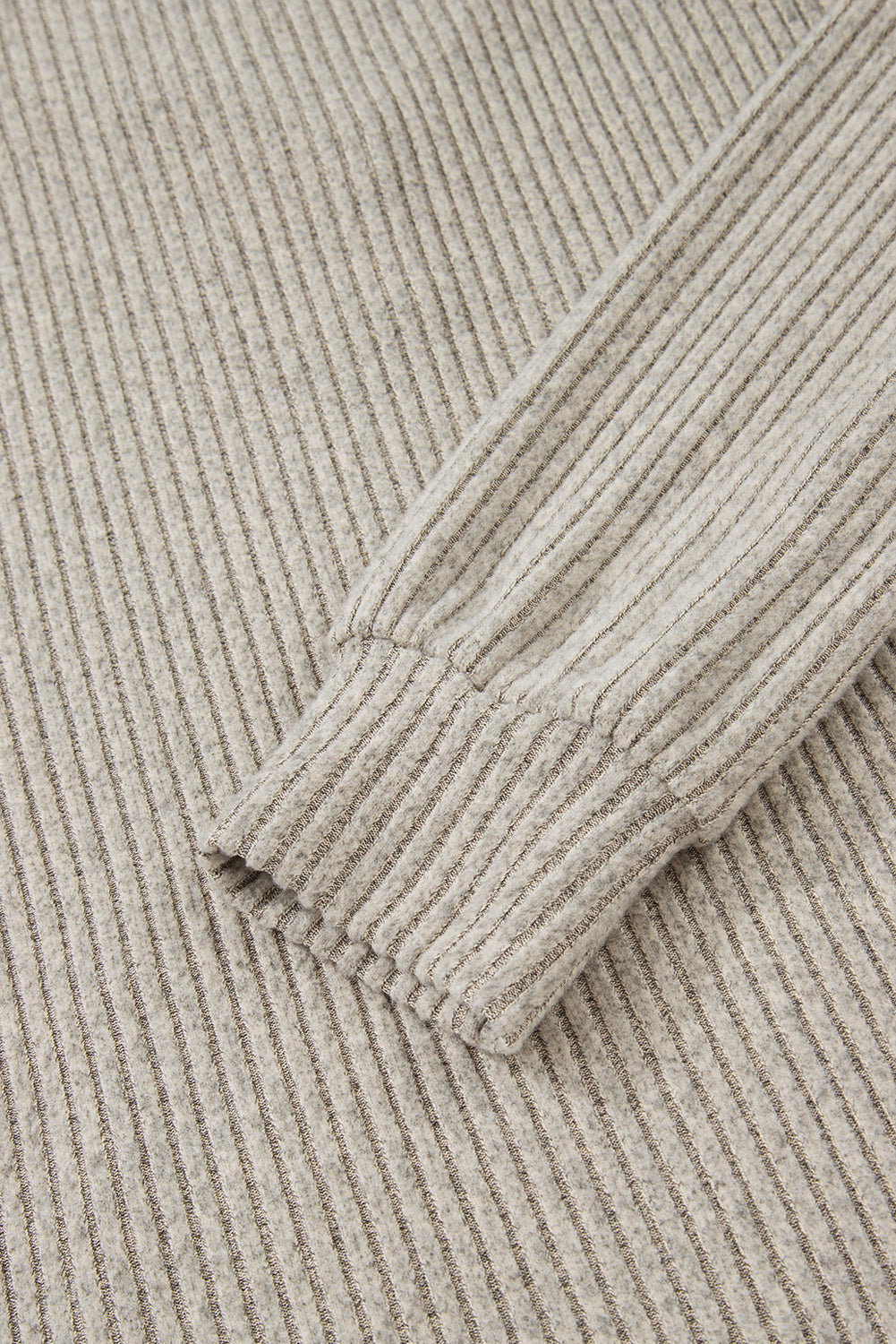 Close-up of beige corduroy fabric with a focus on texture and pattern.