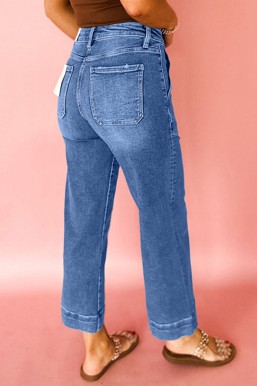 Person wearing blue jeans on a pink background