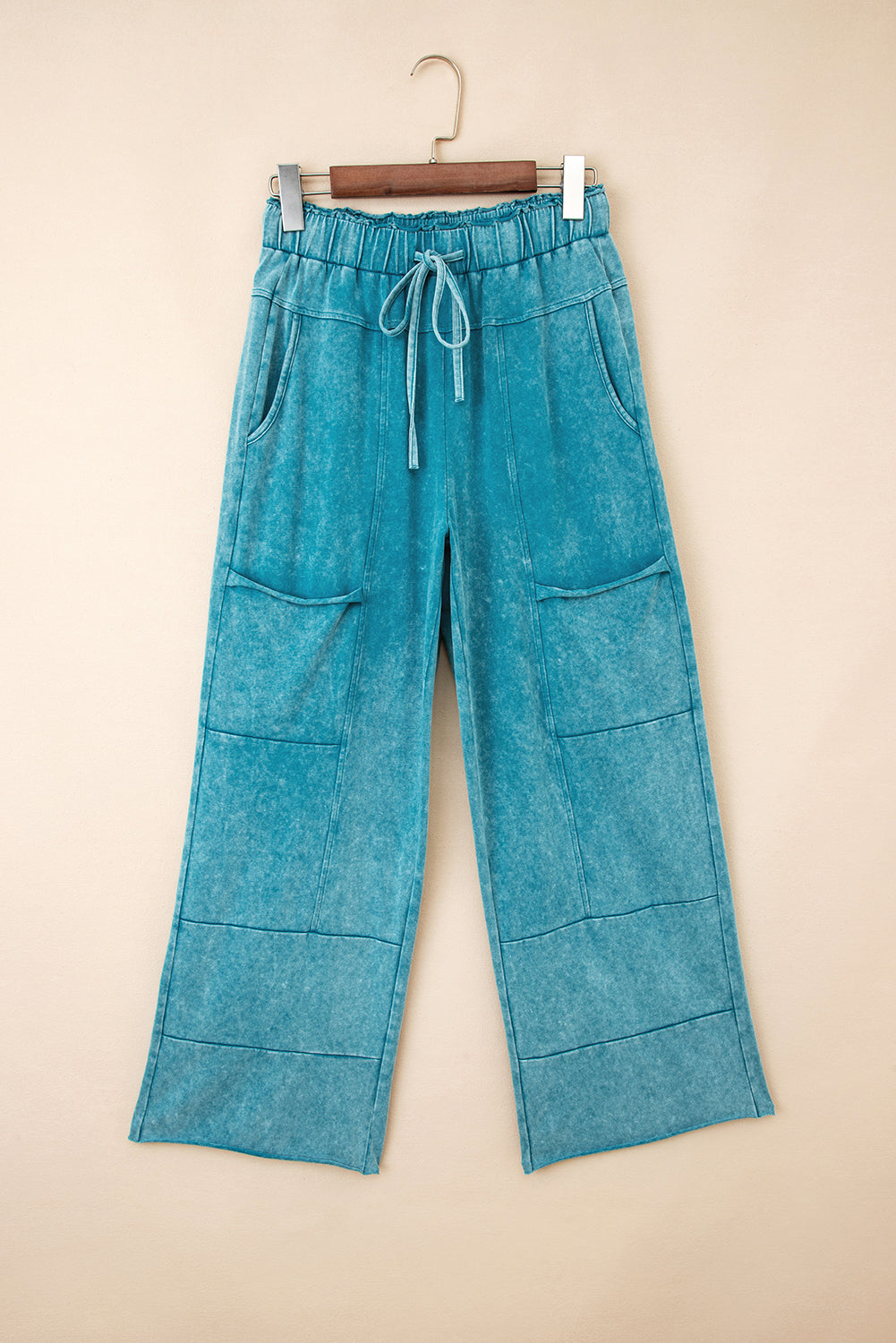 Blue denim pants on a hanger against a beige background