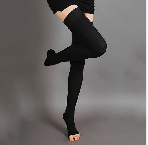 Person wearing black knee-high socks on a gray background