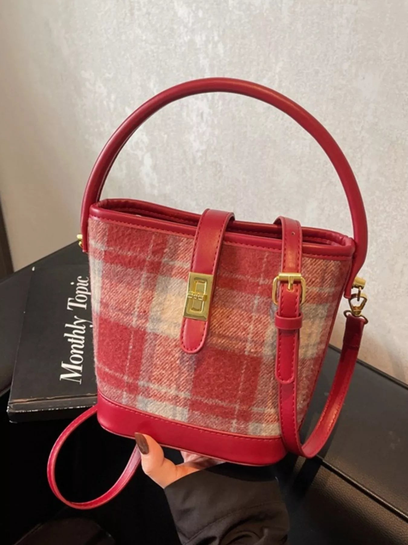 Red plaid handbag with gold accents on a neutral background