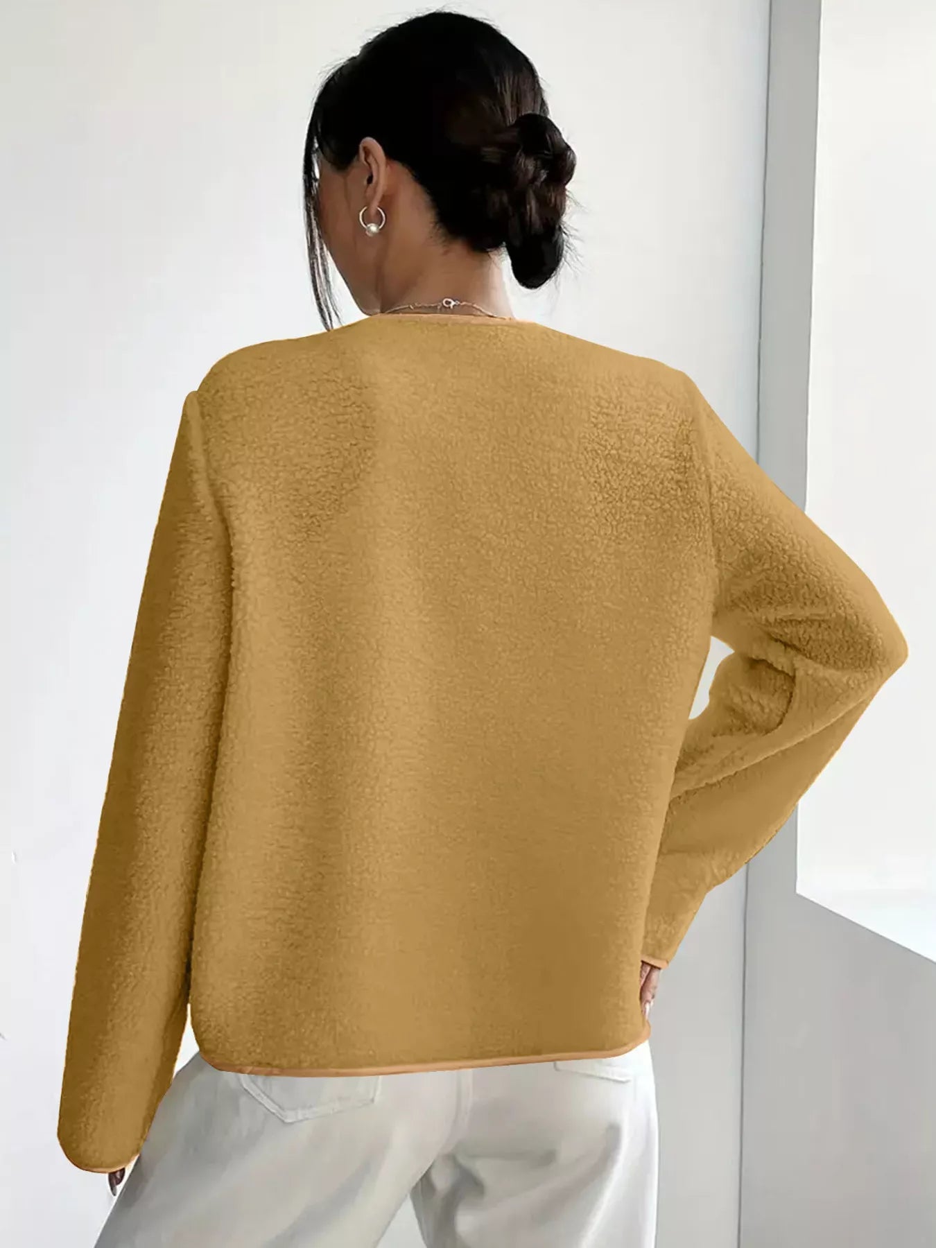 Person wearing a mustard yellow sweater against a white background