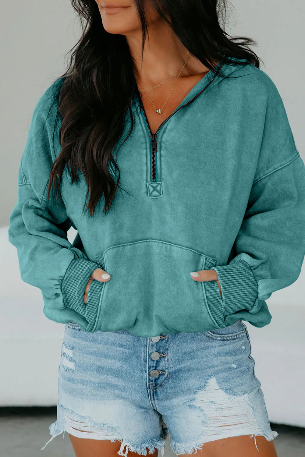Teal hoodie worn by a person with a neutral background