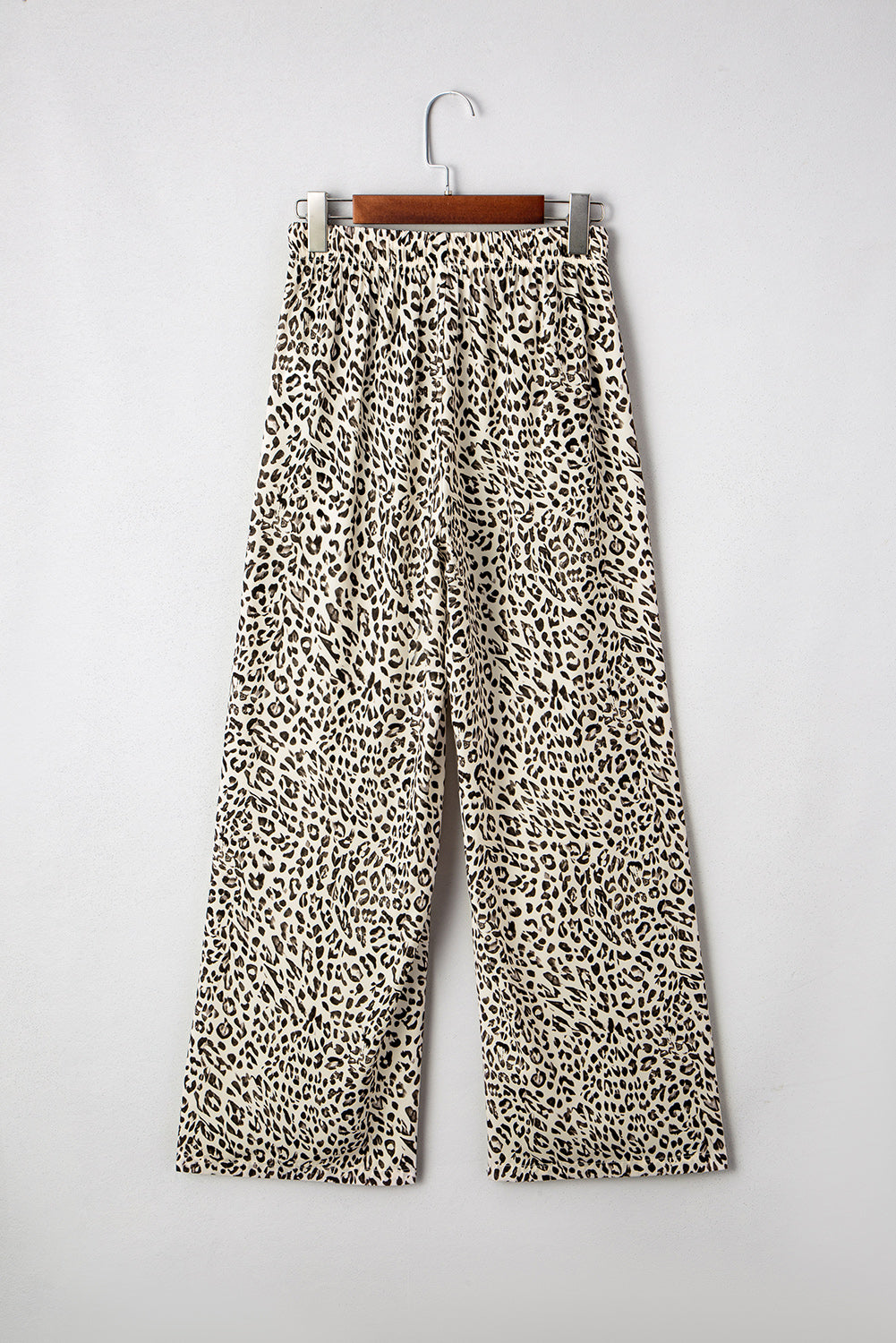 Leopard print pants on a hanger against a white background
