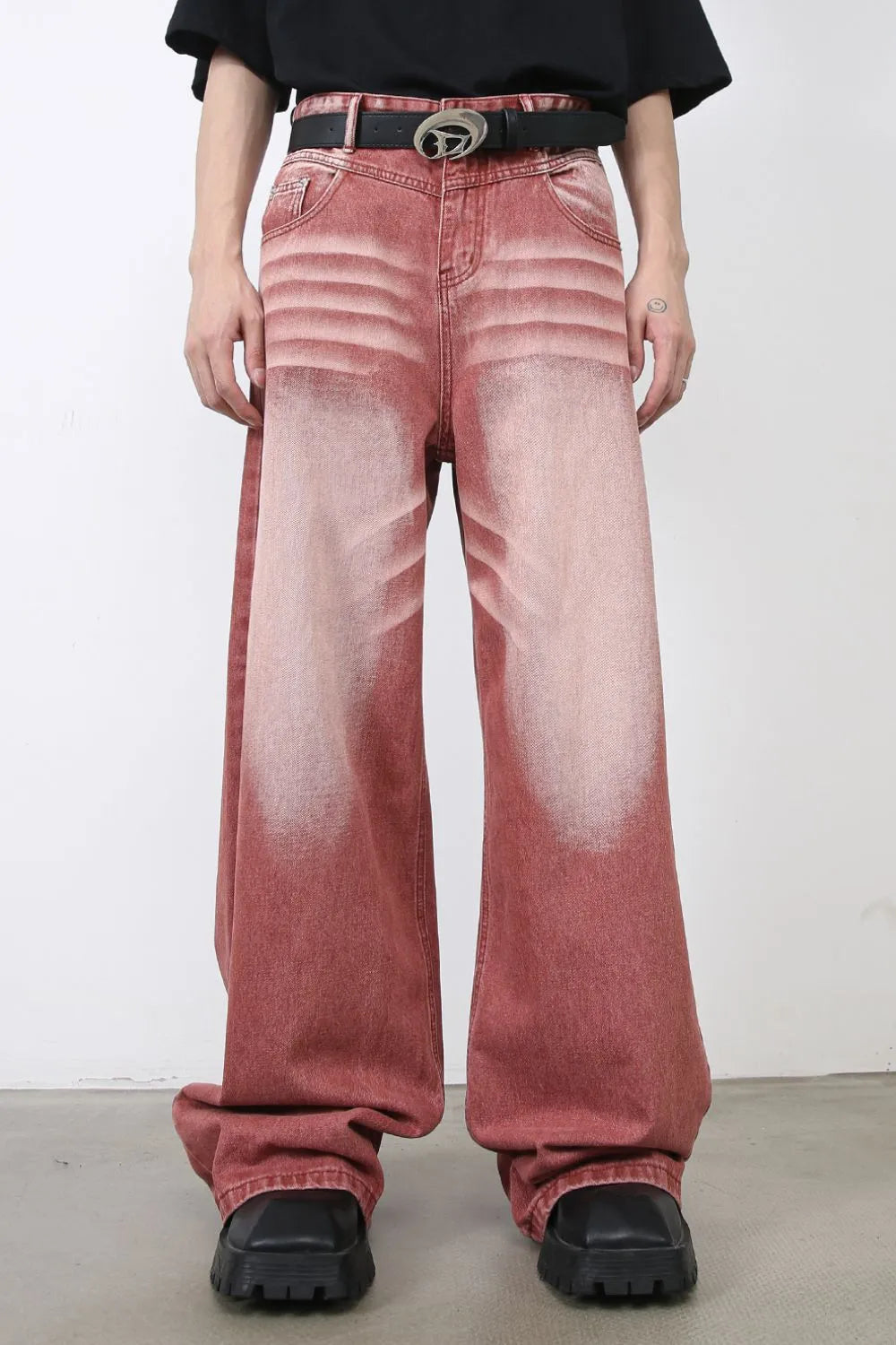 Person wearing rust red acid-wash jeans with a black belt 
