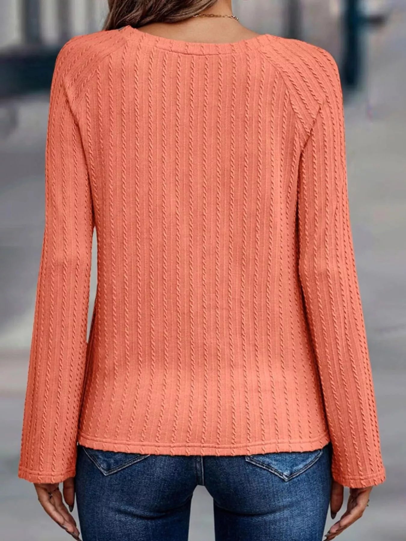 Coral sweater worn by a person with a blurred background