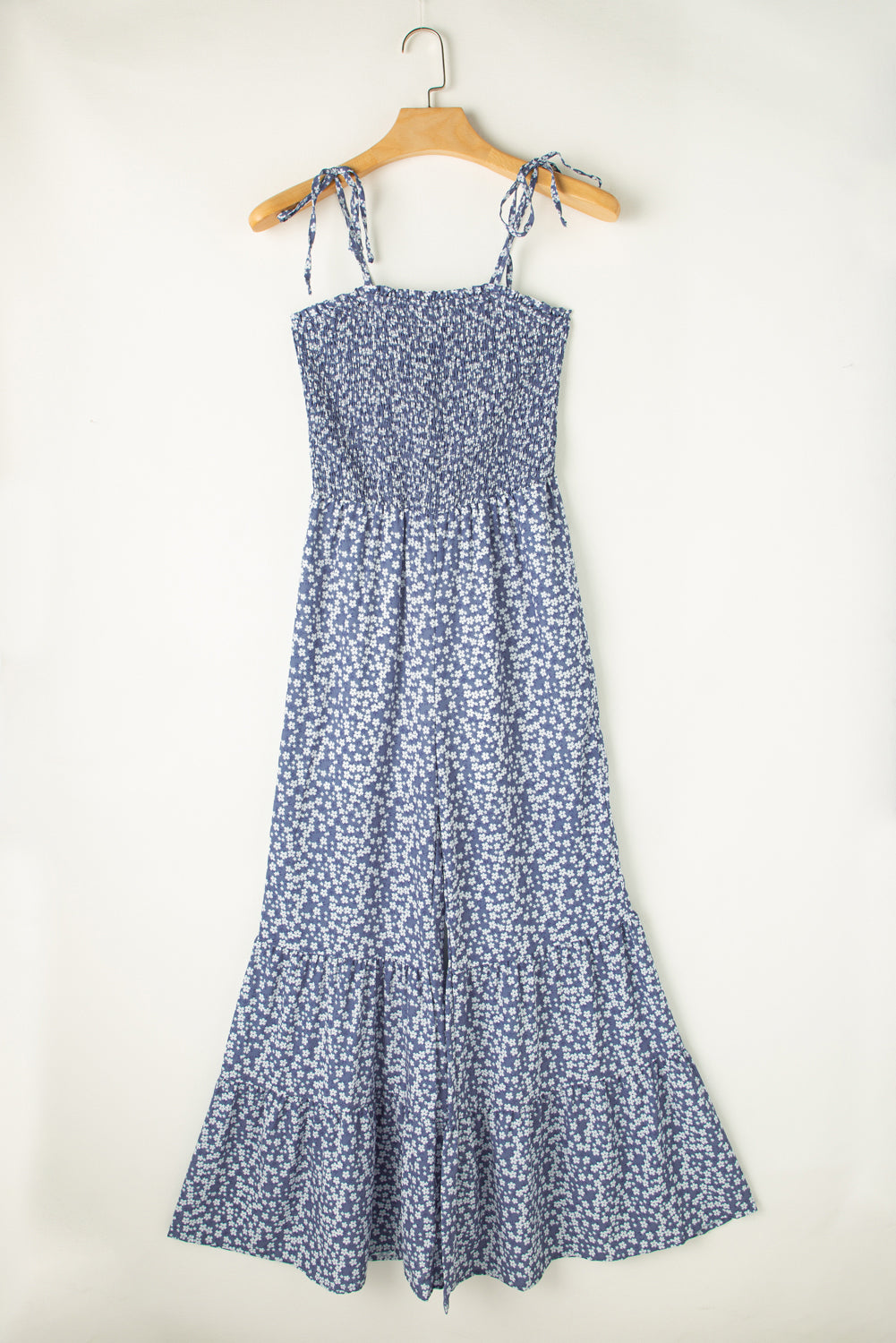 Blue floral dress on a hanger against a white background