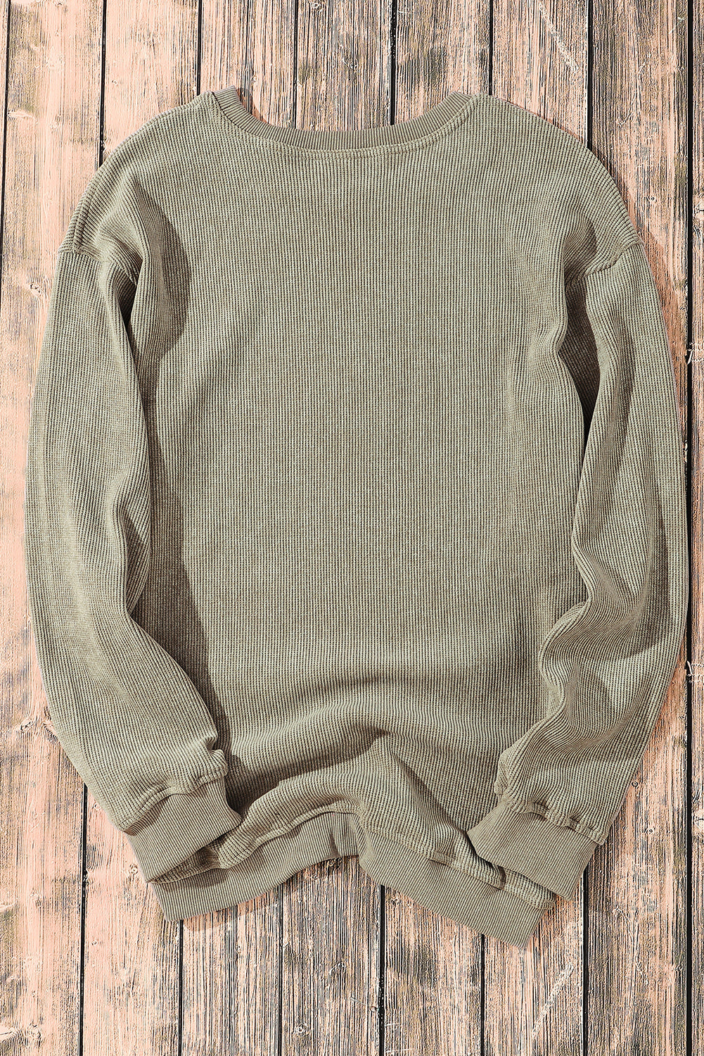 Green ribbed sweater on a wooden surface
