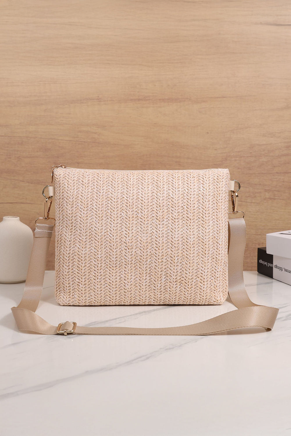 Woven handbag with a strap on a light wooden surface back view
