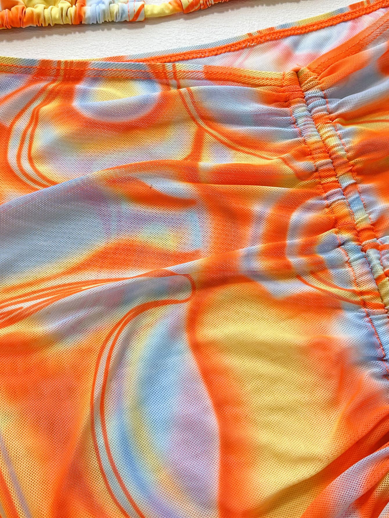 Close-up of a colorful swimsuit with orange, yellow, and white pattern.