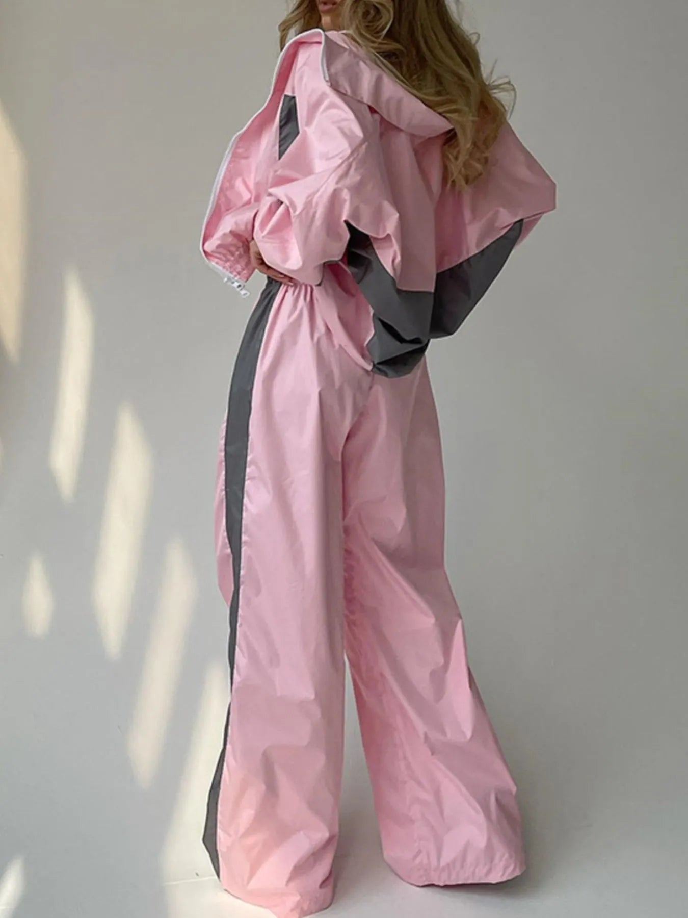 Person wearing a pink and gray outfit against a white wall