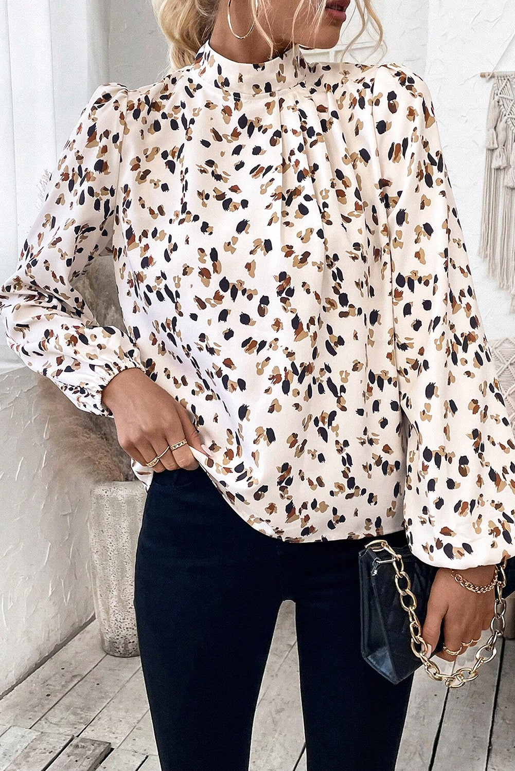 Person wearing a leopard print blouse with black pants indoors.