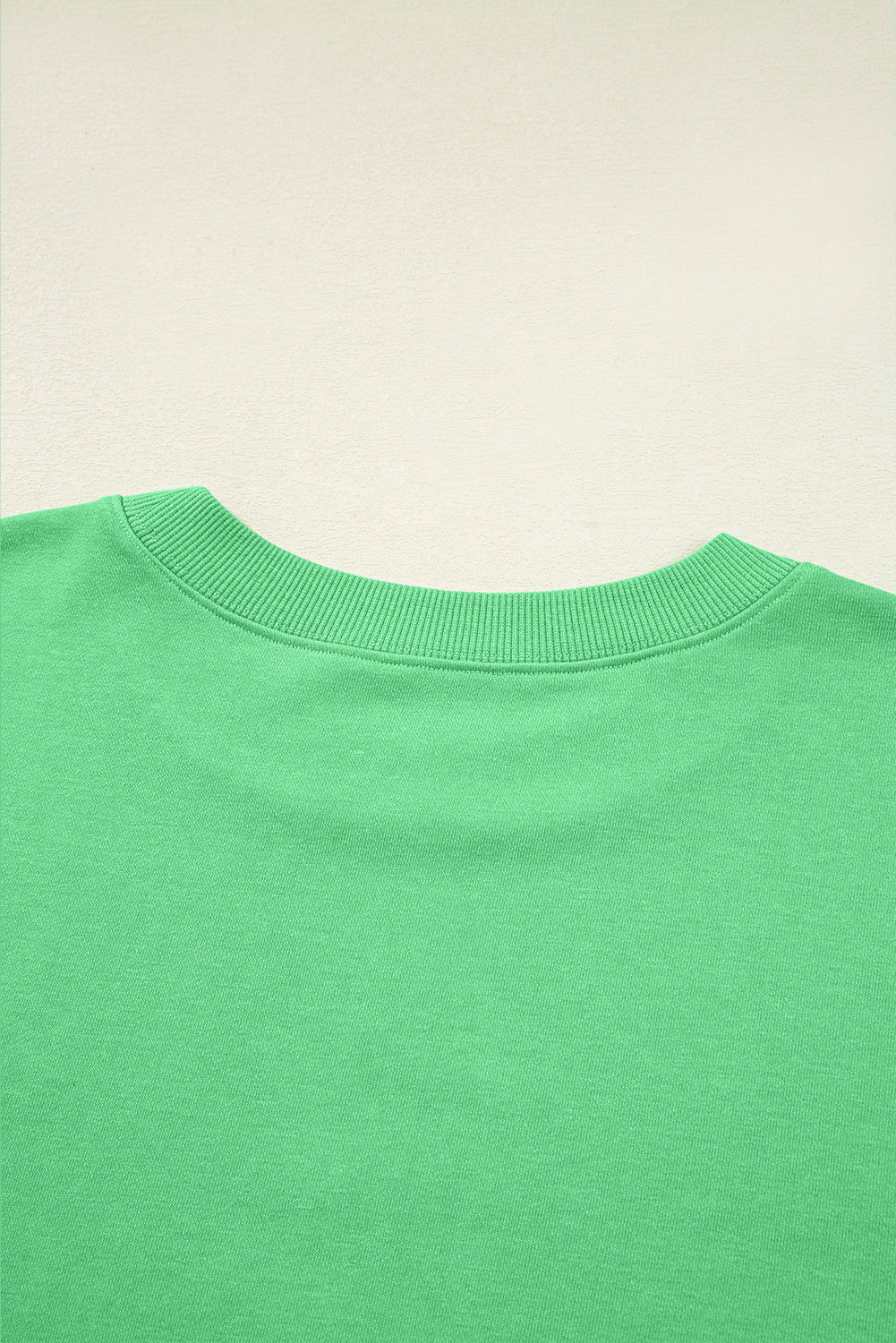 Close-up of a green sweater collar on a beige background