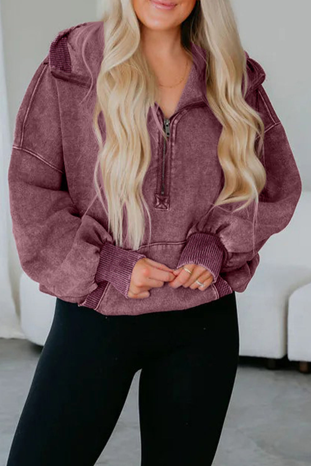 Person wearing a maroon hoodie with a zipper, standing against a white background