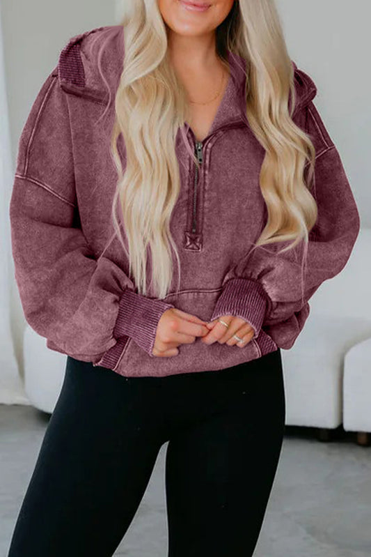 Person wearing a maroon hoodie with a zipper, standing against a white background