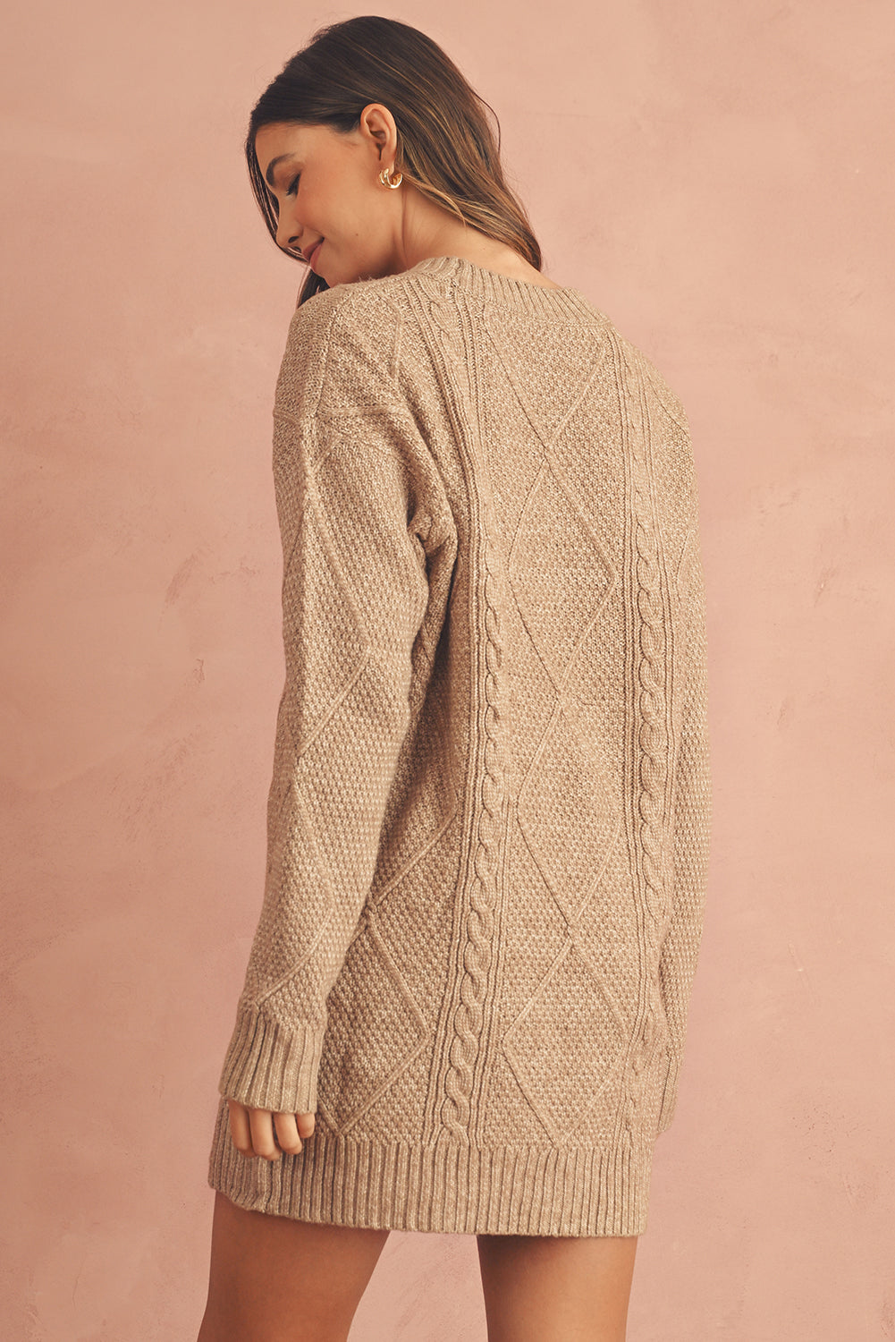 Woman wearing a beige cable knit sweater back view