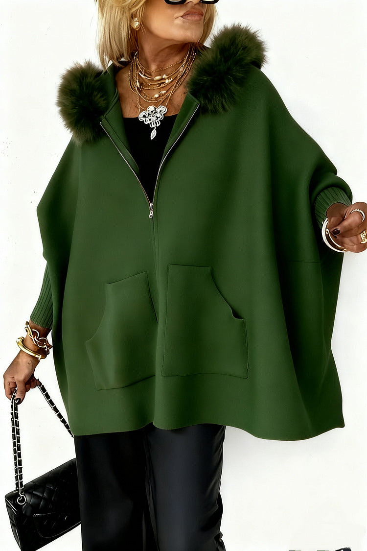 Woman wearing a green poncho with fur hood on a white background