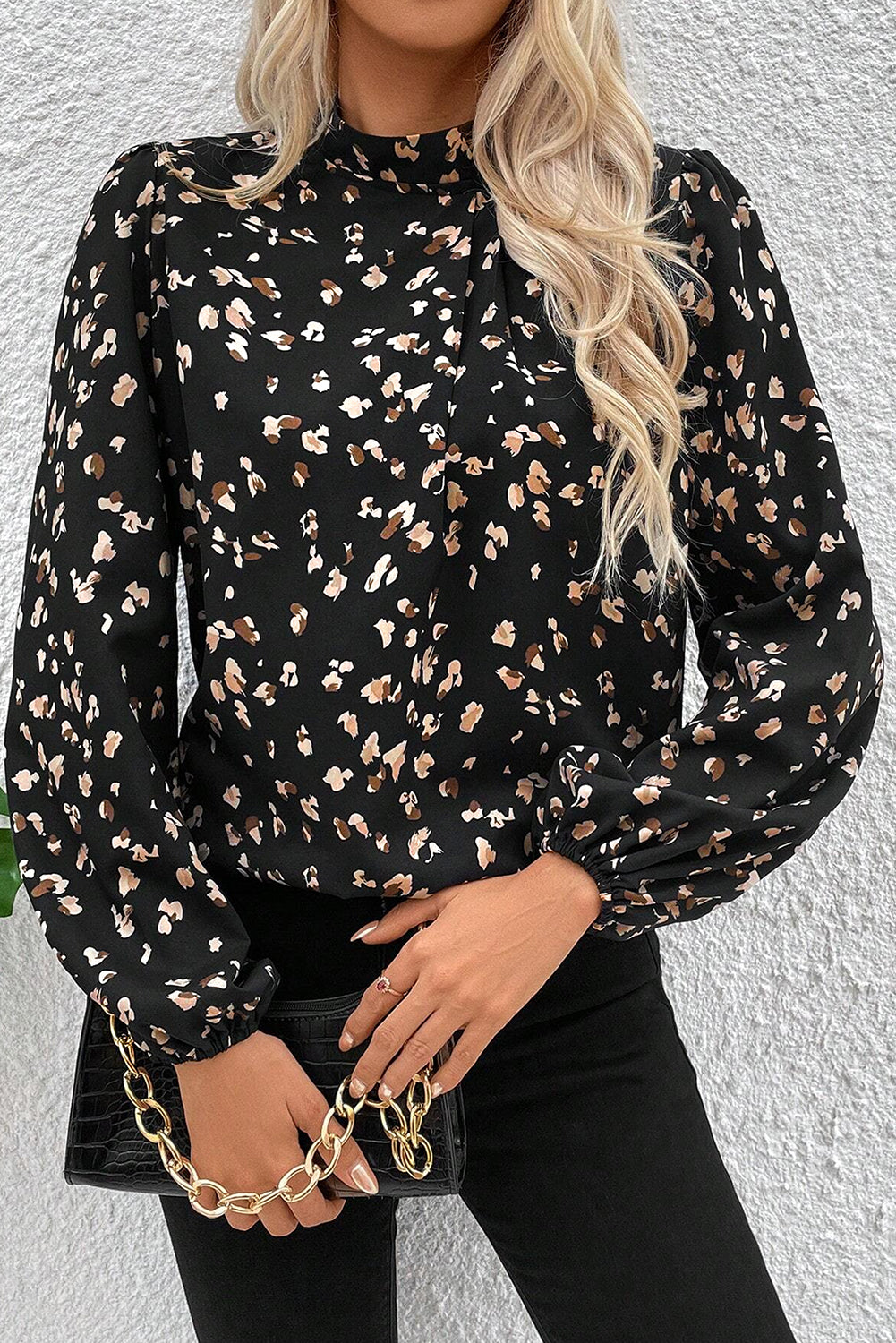 Woman wearing a black floral blouse against a white wall
