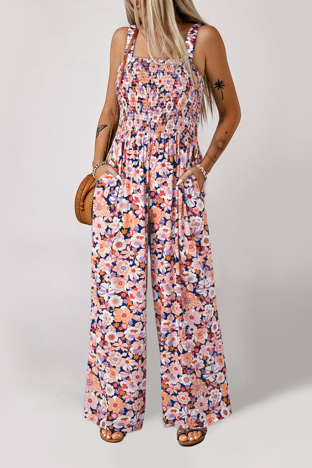 Woman wearing a floral peach jumpsuit on a plain background