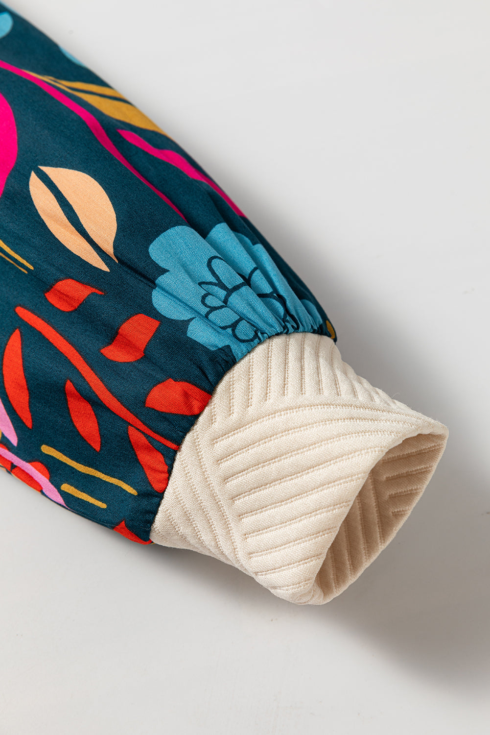 Colorful fabric with abstract patterns and a textured beige edge on a light gray background