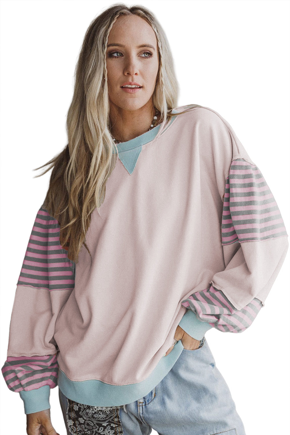 Woman wearing a light pink sweater with striped sleeves on a white background