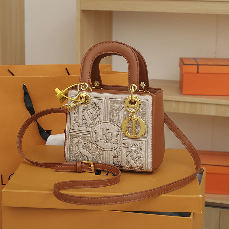 Designer handbag with gold charms on a yellow box with orange boxes in the background