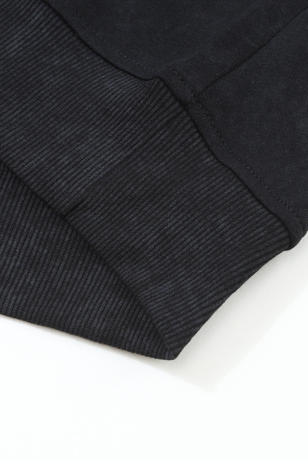 Close-up of a black ribbed sweater sleeve on a white background