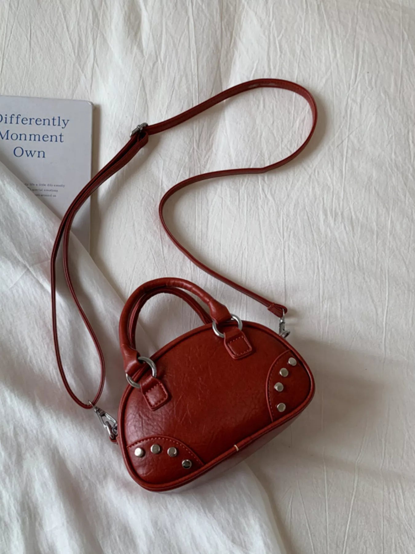 Red handbag with a strap on a white surface