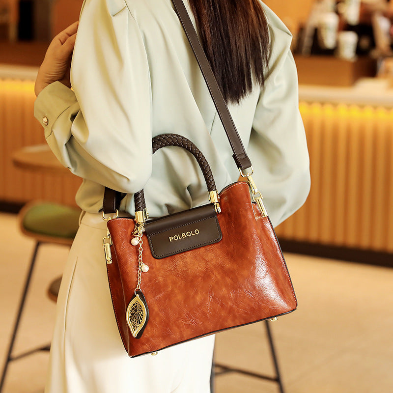 Brown handbag with gold accents held by a person in an indoor setting