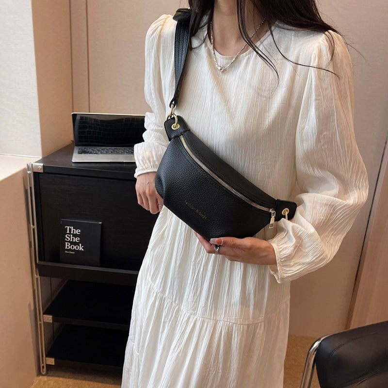 Person holding a black bag with a laptop on a desk labeled 'The She Book' in the background