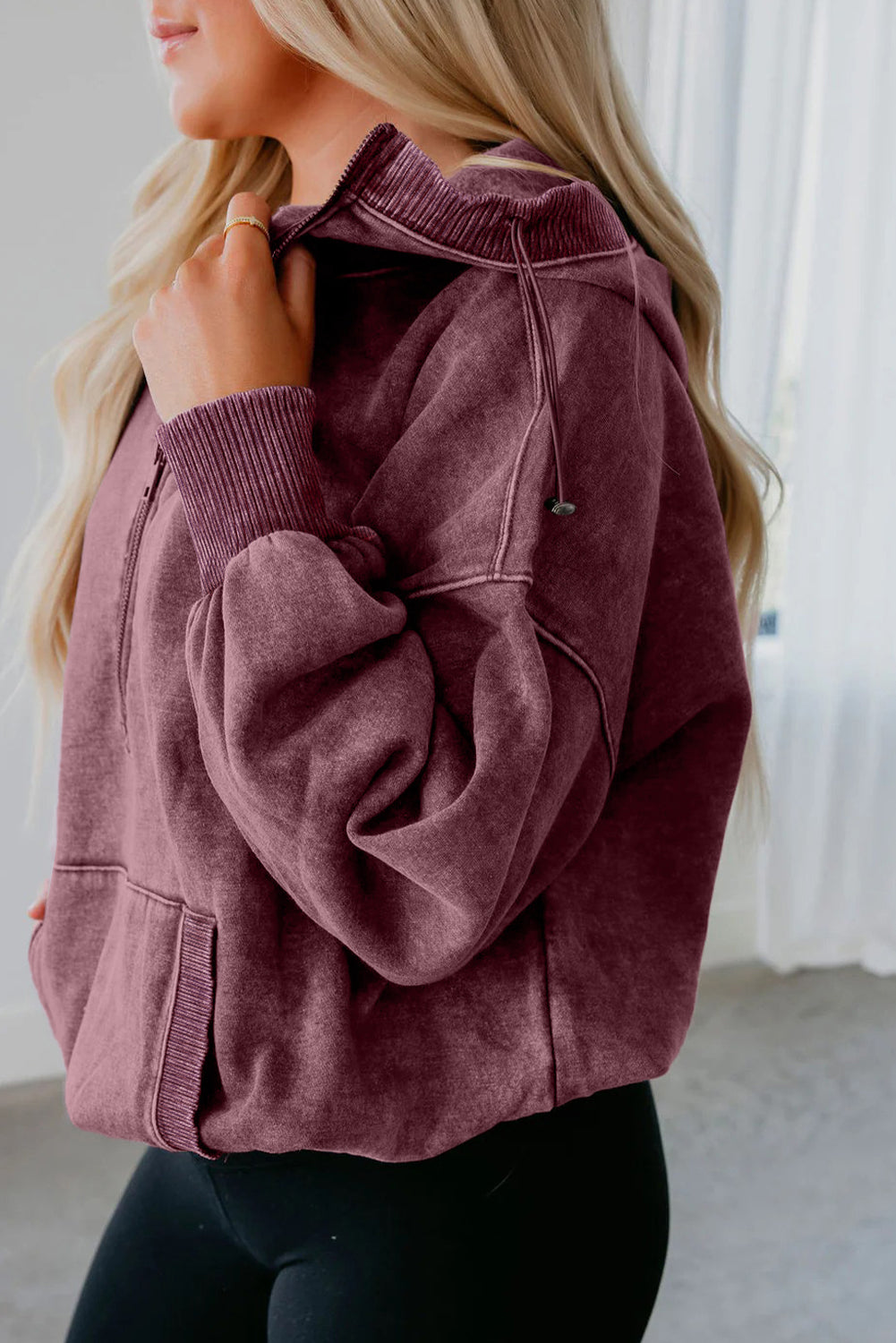 Person wearing a maroon jacket in a neutral setting