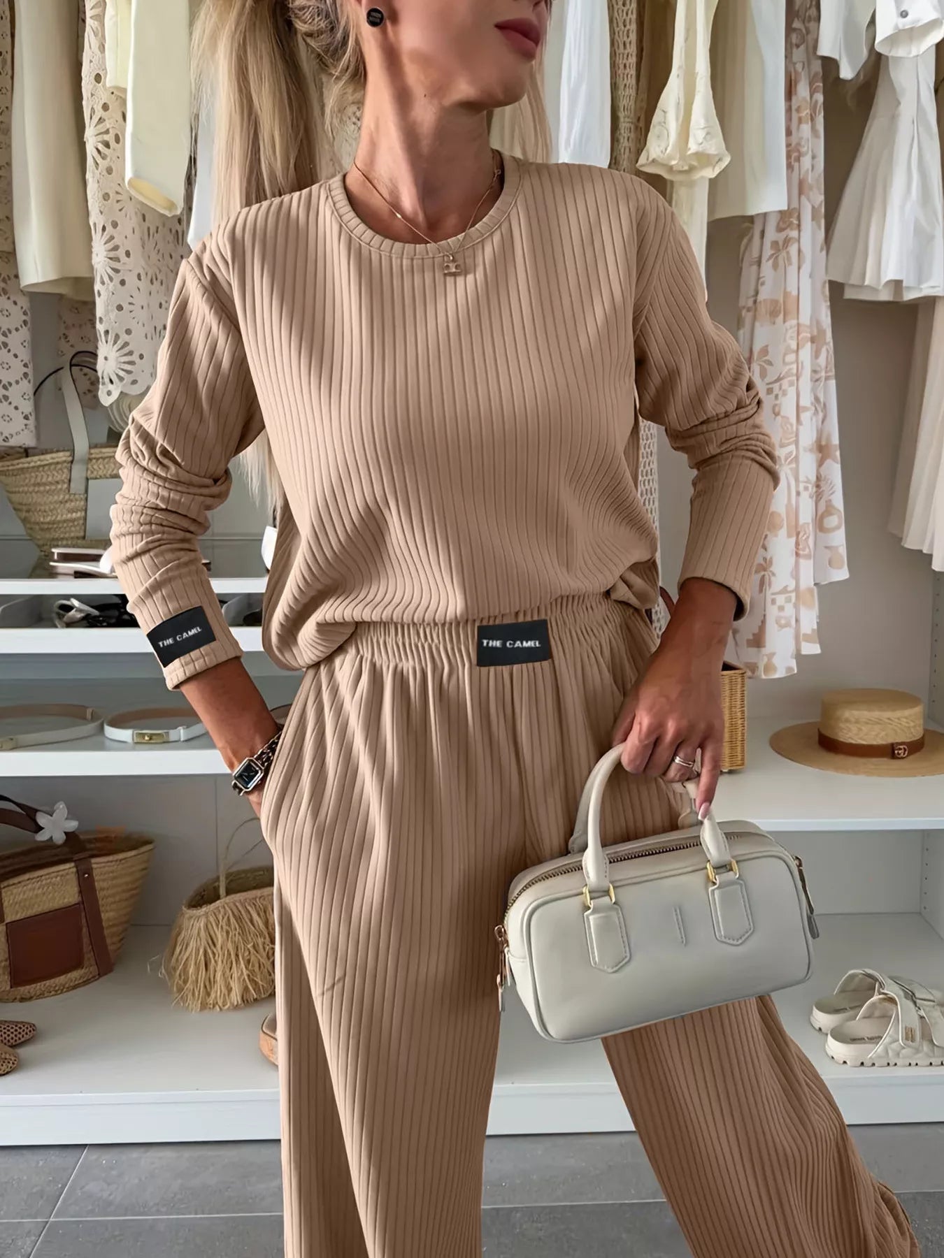Woman in a beige outfit holding a white handbag in a clothing store.
