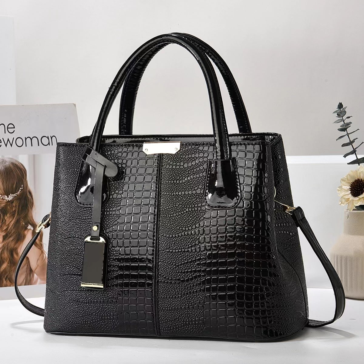 Black textured handbag on a white surface with a blurred background