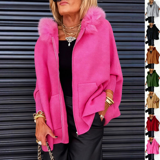 Woman wearing a bright pink jacket with fur hood against a metallic background