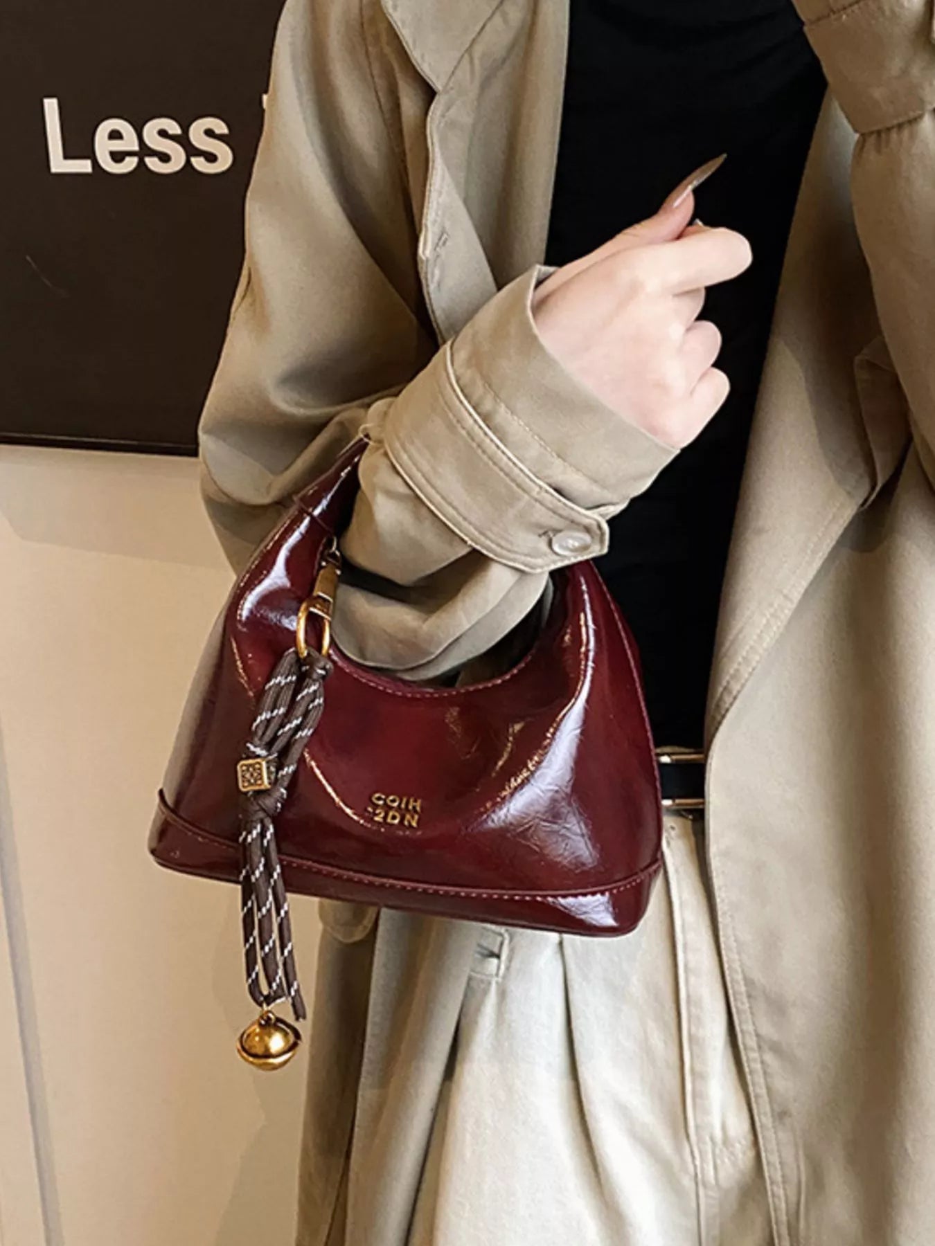 Person holding a red handbag with a gold clasp, wearing a beige coat.