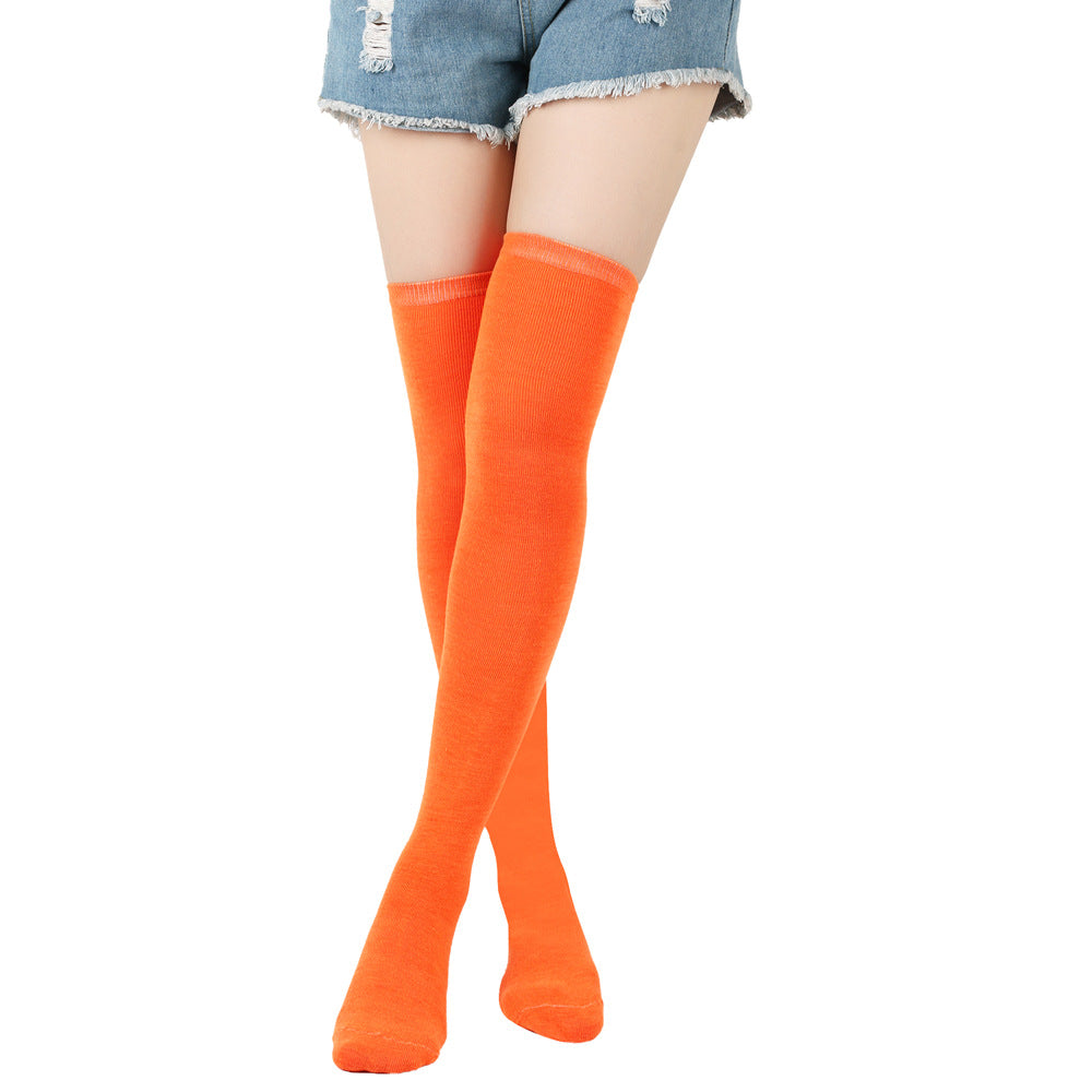 Orange knee-high socks worn with denim shorts on a white background