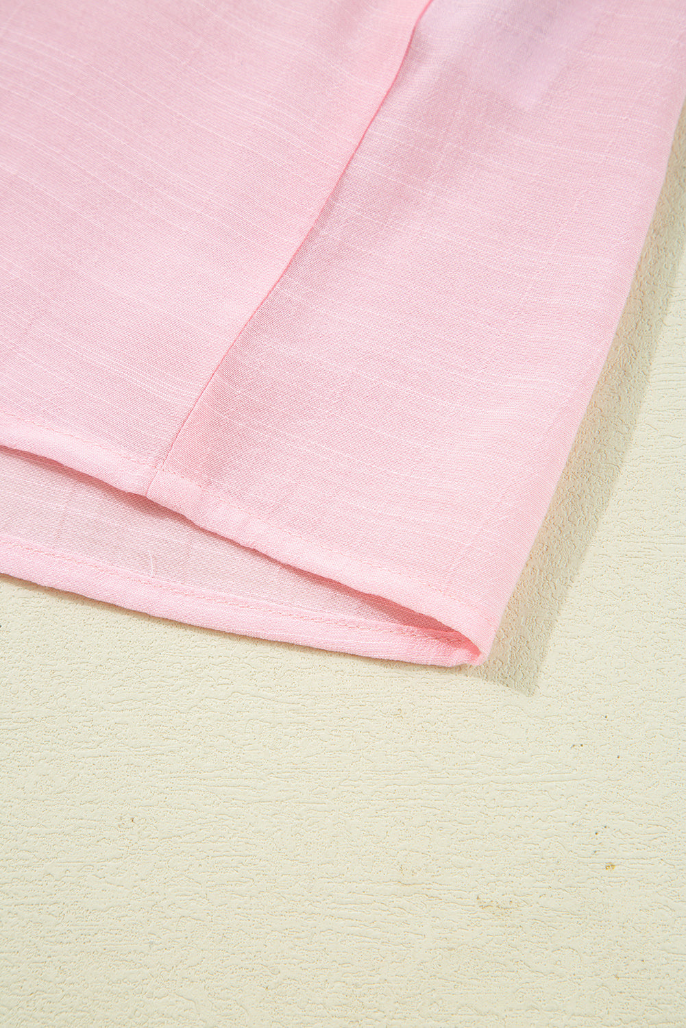 Close-up of pink fabric on a textured beige surface