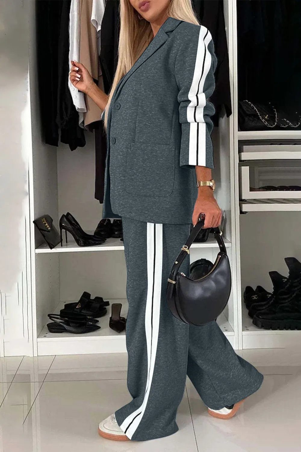 Woman in a gray suit with white stripes standing in a closet.