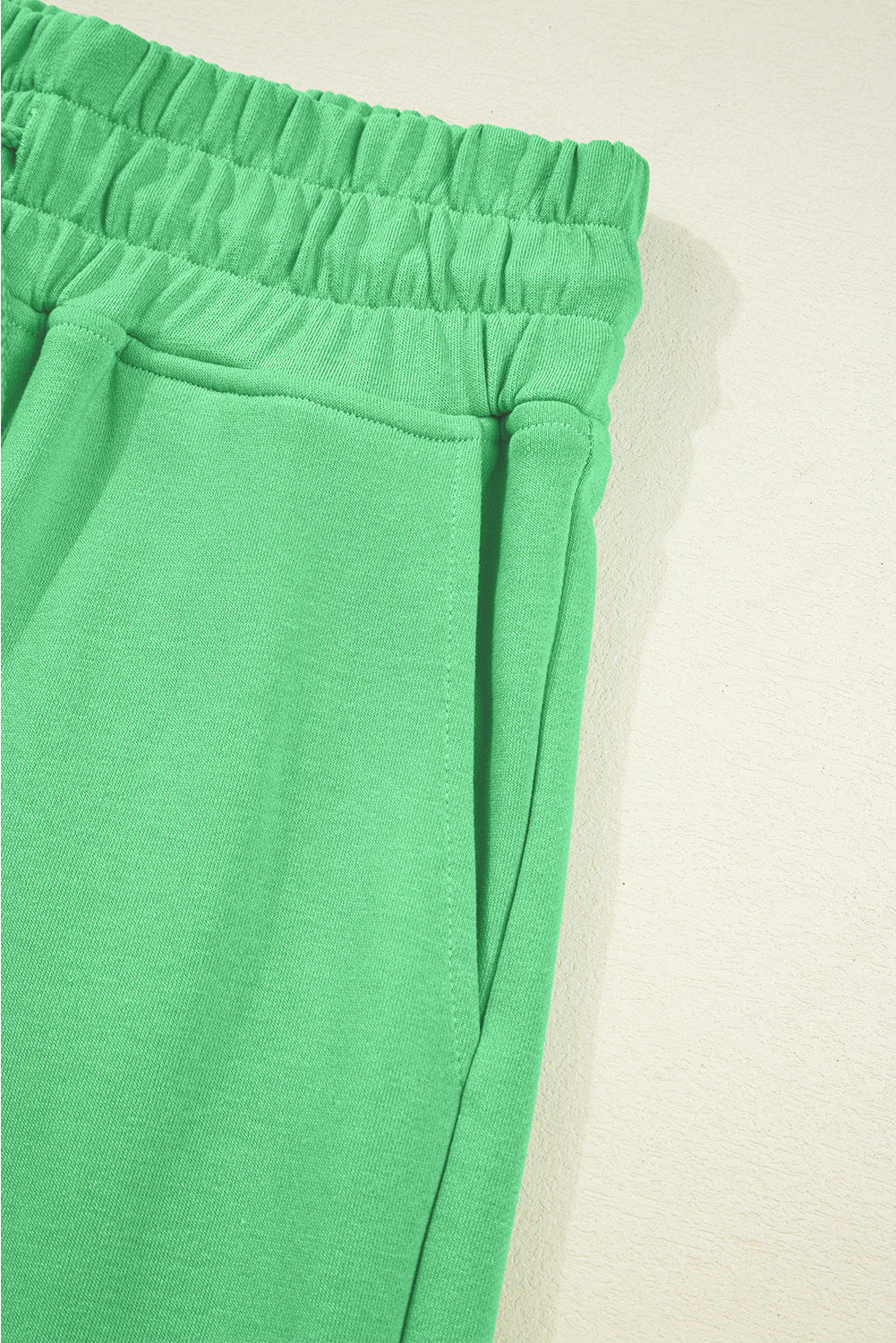 Close-up of green pants with an elastic waistband on a beige background