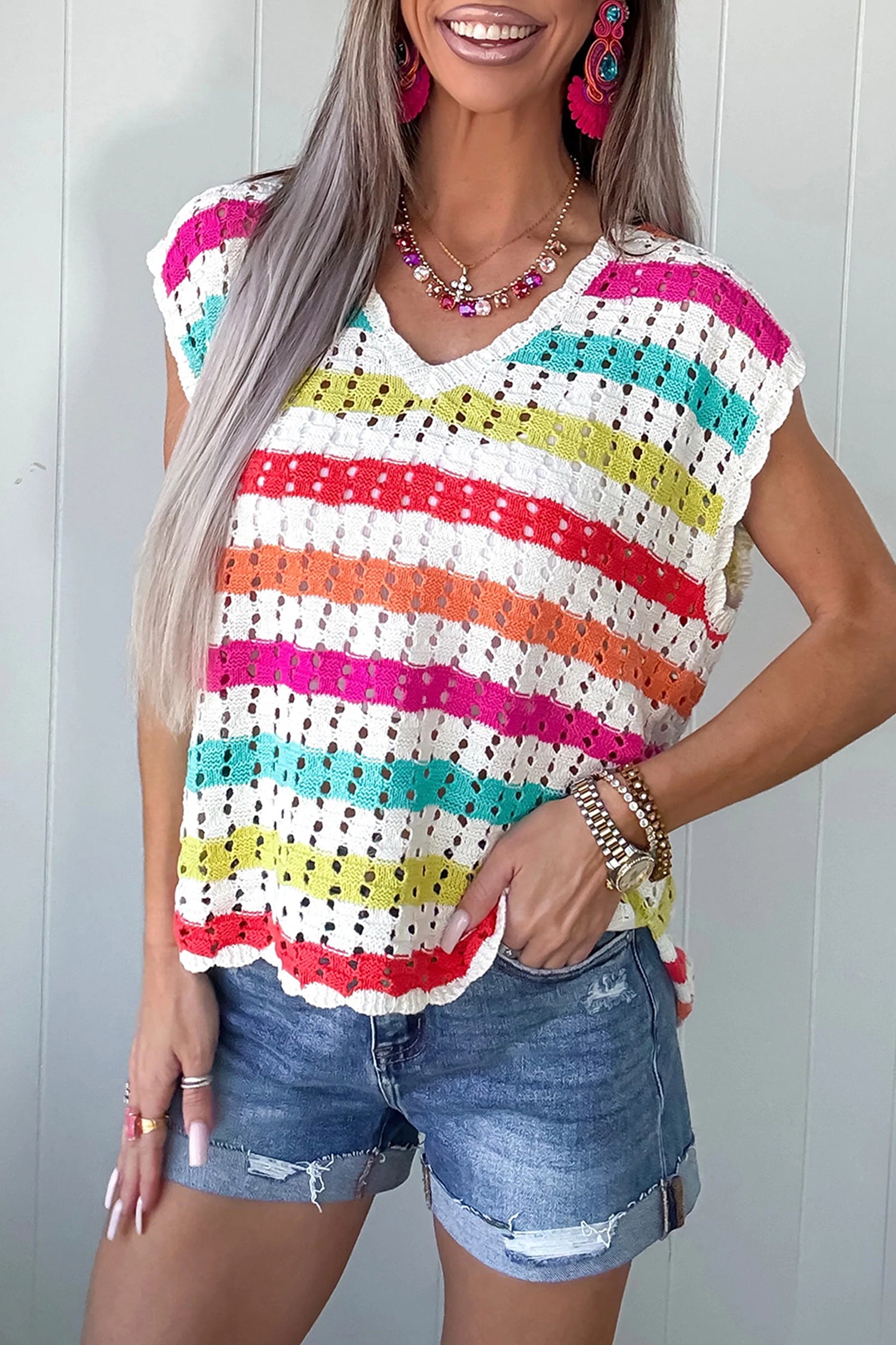 Woman wearing a colorful striped top and denim shorts against a white background