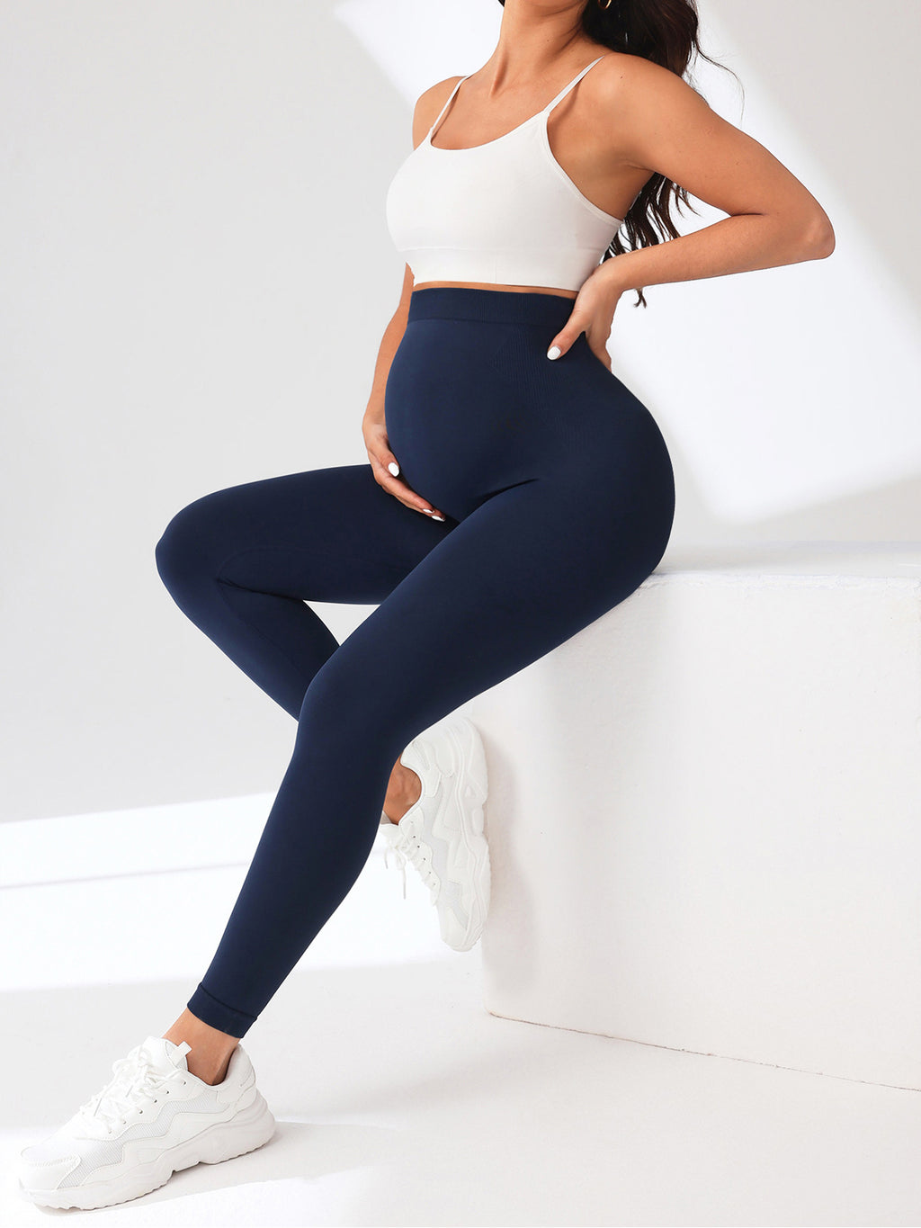 Person wearing navy leggings and a white top on a white background