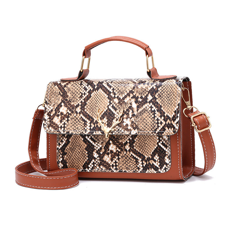 Snake print handbag with brown leather accents on a white background