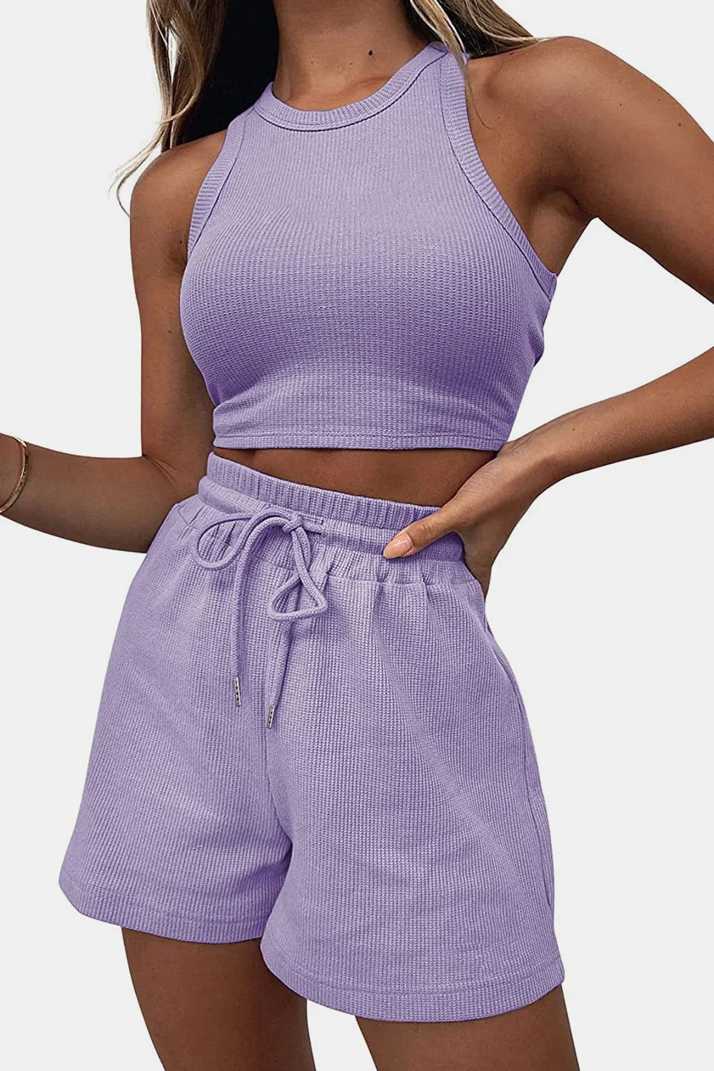 Person wearing a matching purple tank top and shorts set on a plain background