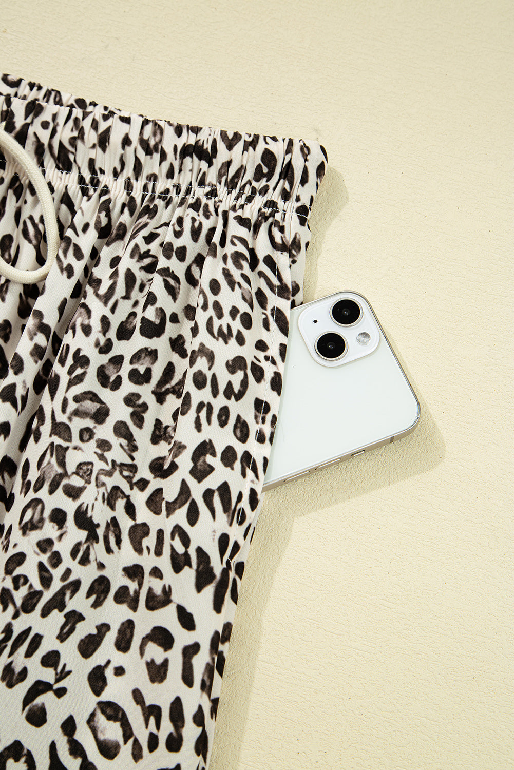 Leopard print pants with a smartphone on a beige background