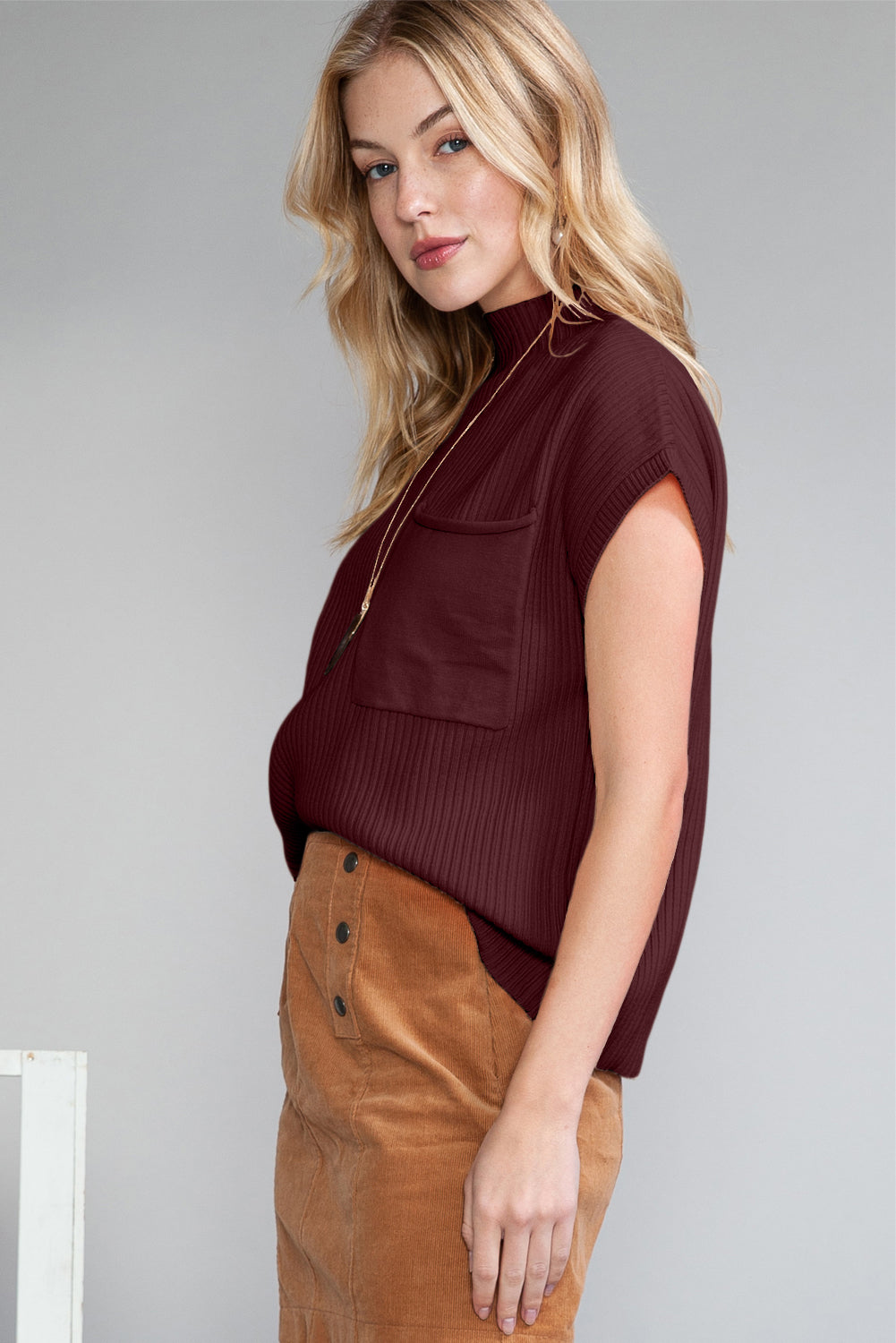 Woman wearing a burgundy top and brown skirt against a plain background