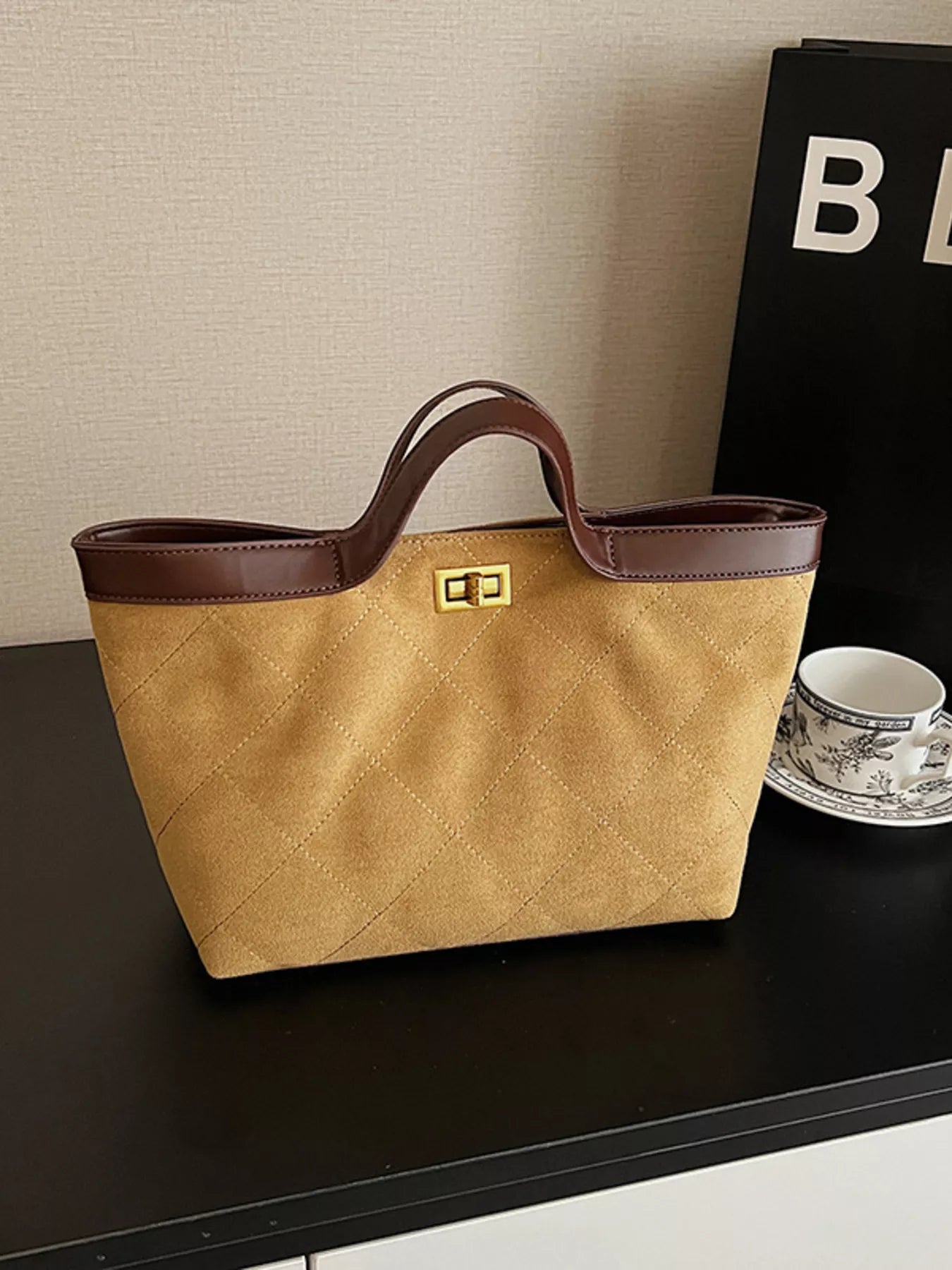 Beige handbag with brown handle on a dark surface