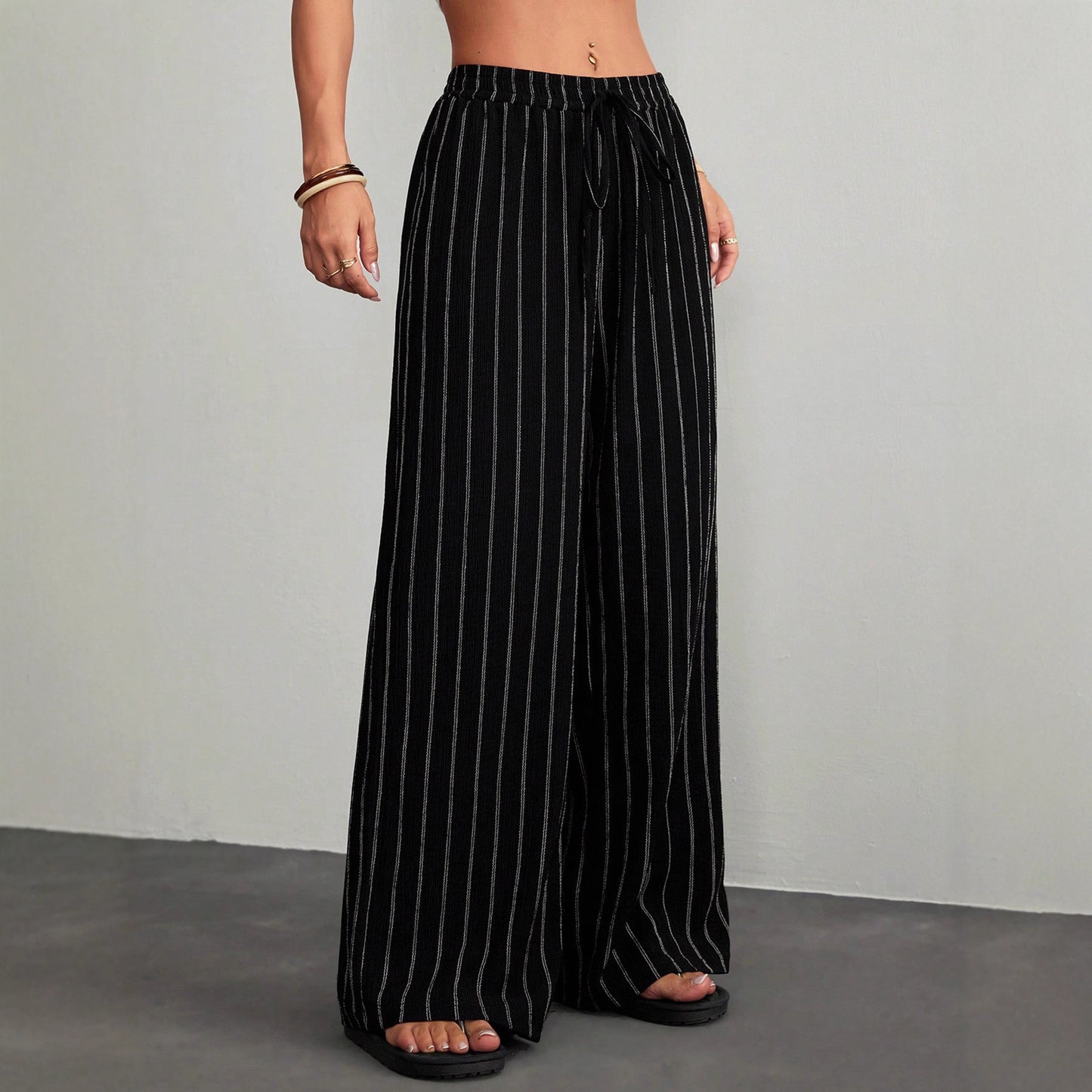 Black pinstripe pants worn by a person on a gray background