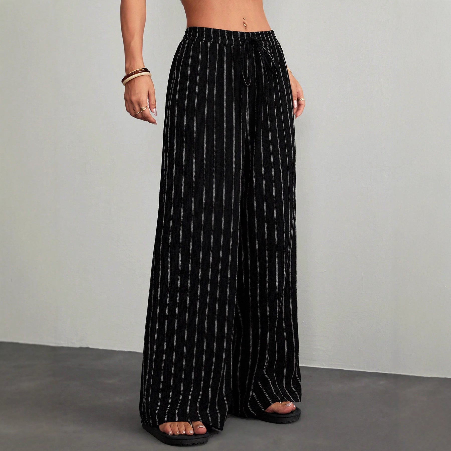 Black pinstripe pants worn by a person on a gray background